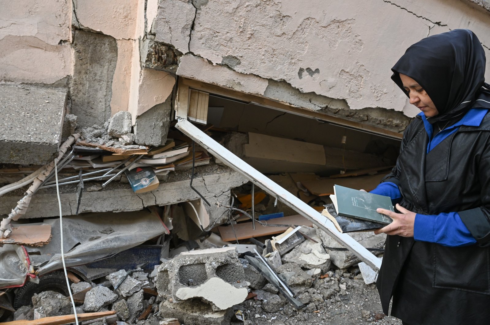 Mürüvet Alparslan Nazlı collects her father&#039;s books from under the rubble in Kahramanmaraş, southeastern Türkiye, March 25, 2023. (AA Photo)