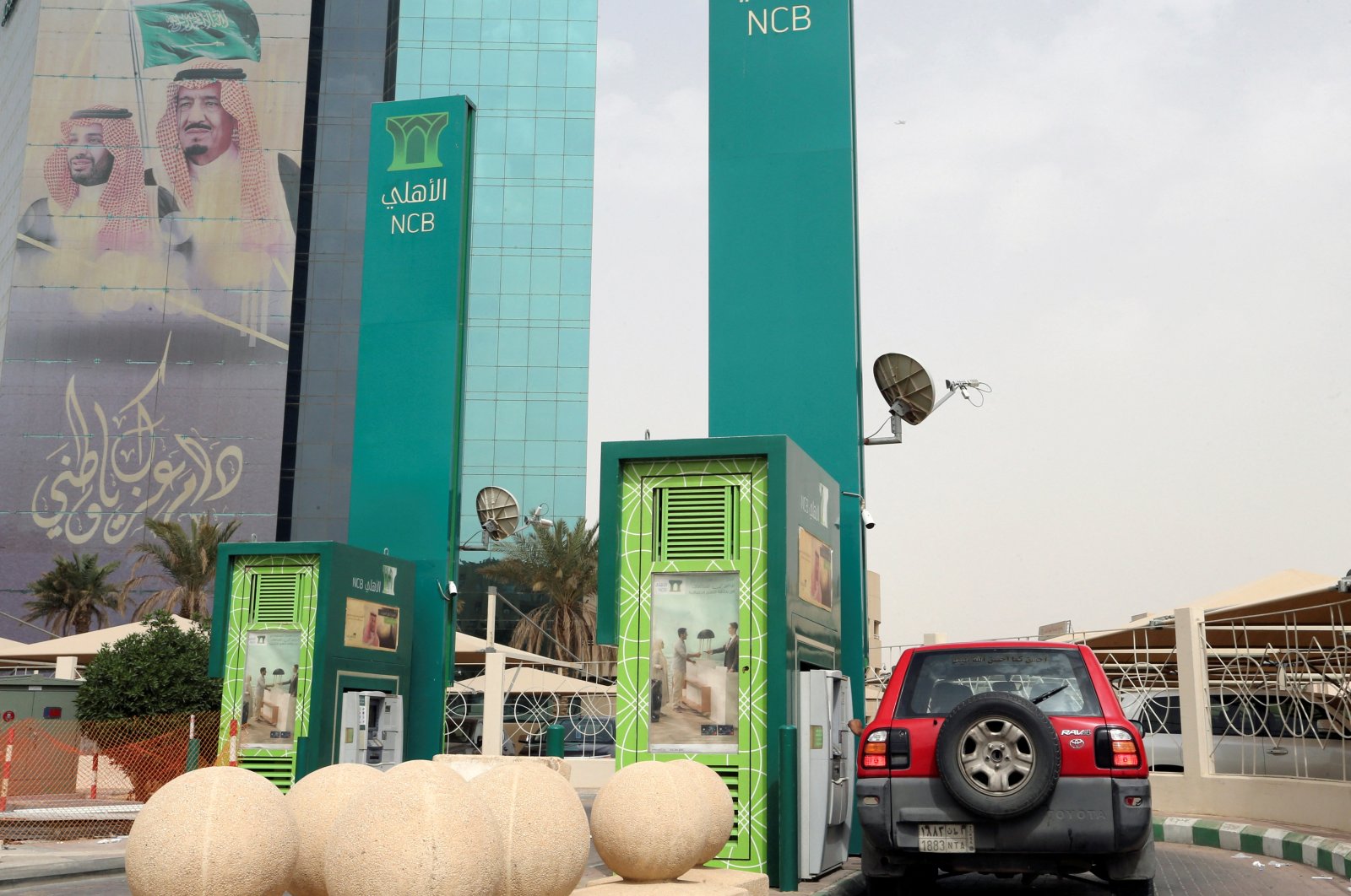 A man in a car withdraws money from an ATM outside the Saudi National Commercial Bank (NCB), in Riyadh, Saudi Arabia, March 18, 2020. (Reuters Photo)