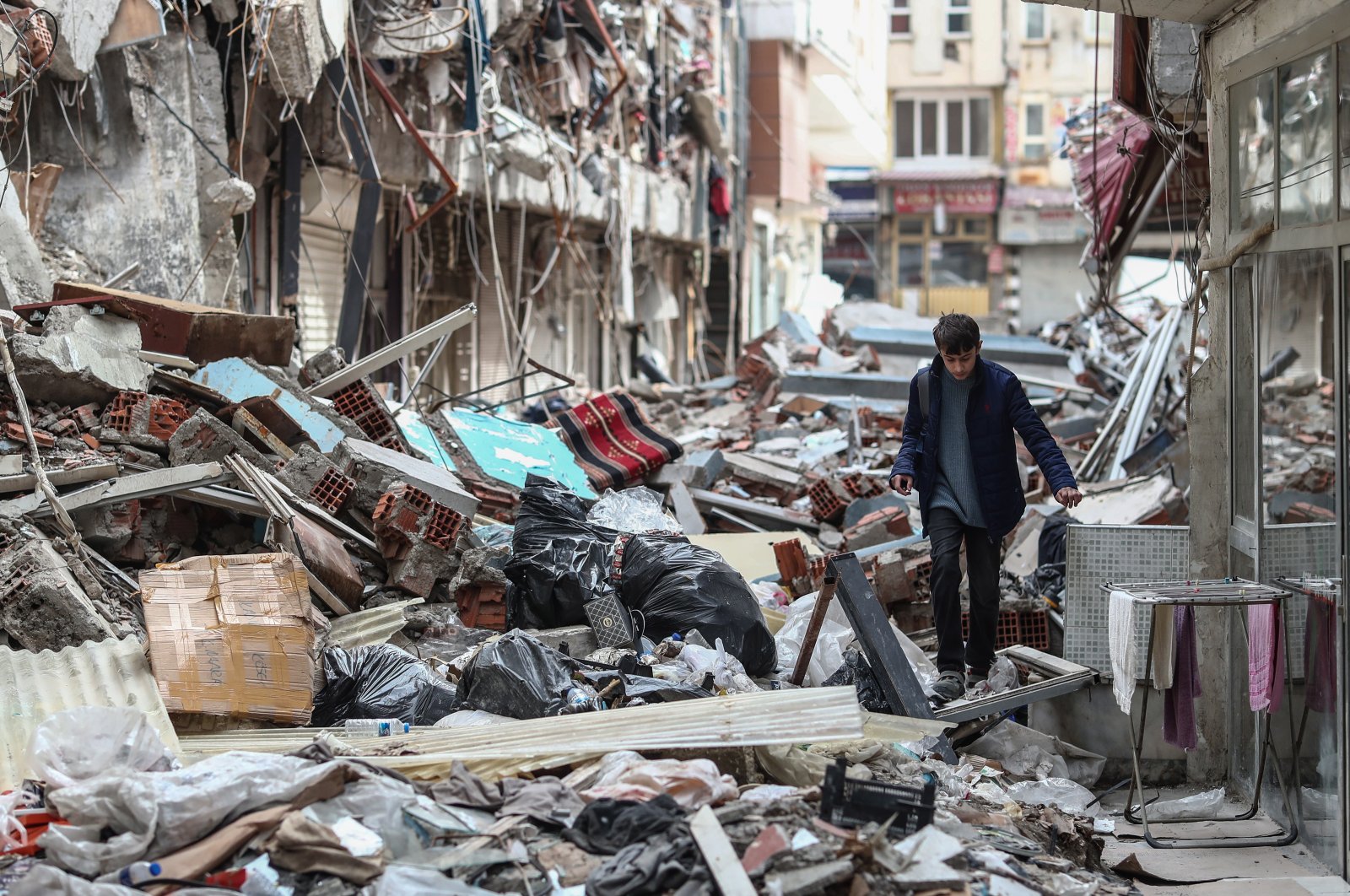 A boy walks among the ruble of collapsed buildings on the eve of Ramadan, in the aftermath of the powerful earthquakes in Kahramanmaraş, Türkiye, March 22, 2023. (EPA Photo)