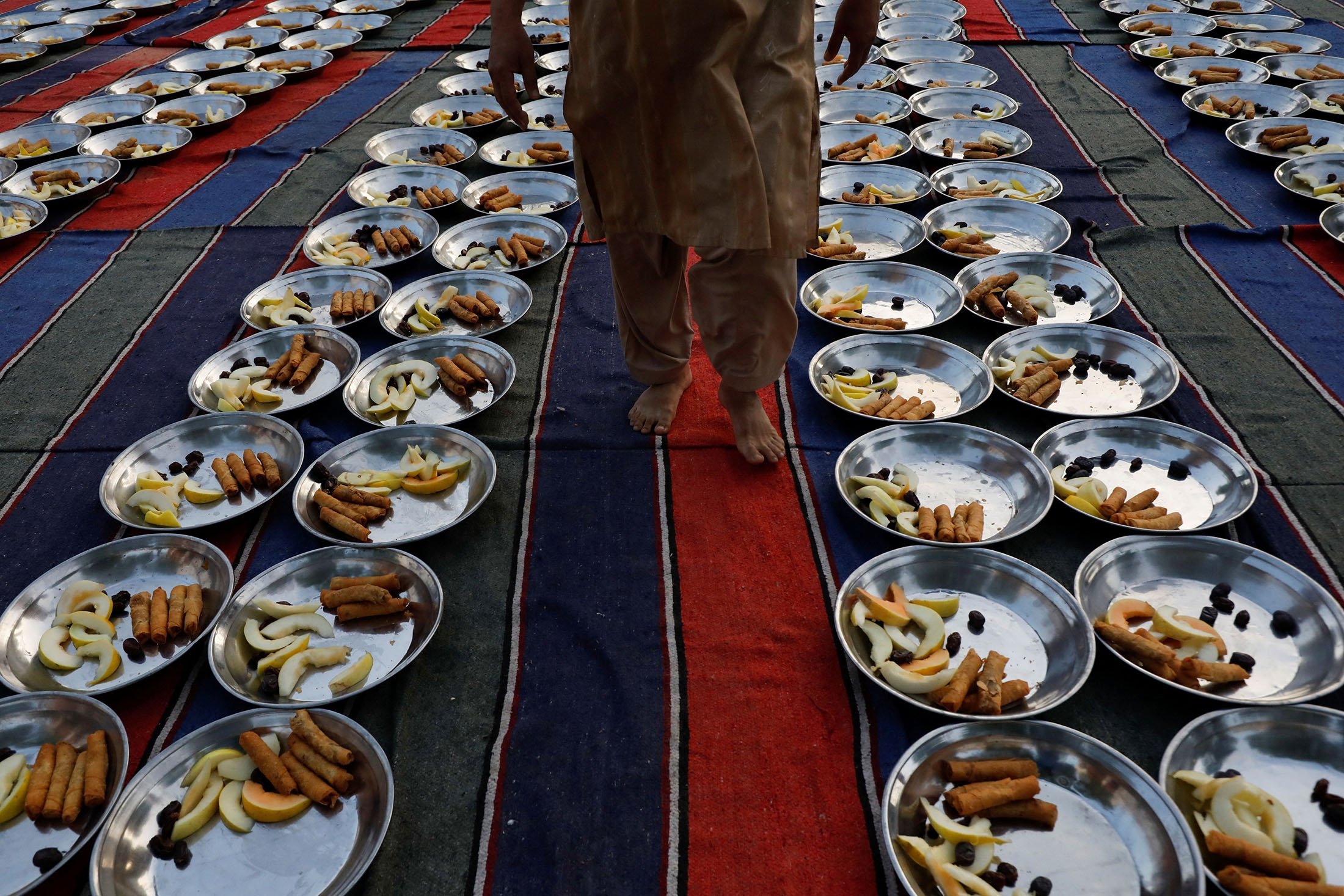 Seorang pria berjalan untuk memeriksa panel makanan sebelum berbuka puasa atau waktu berbuka puasa, selama bulan Ramadhan, di Karachi, Pakistan, 23 Maret 2023. (Foto Reuters)