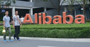 Staff members walk past the logo of Chinese e-commerce giant Alibaba at its headquarters in Hangzhou, in China's eastern Zhejiang province, May 27, 2022. (AFP Photo)