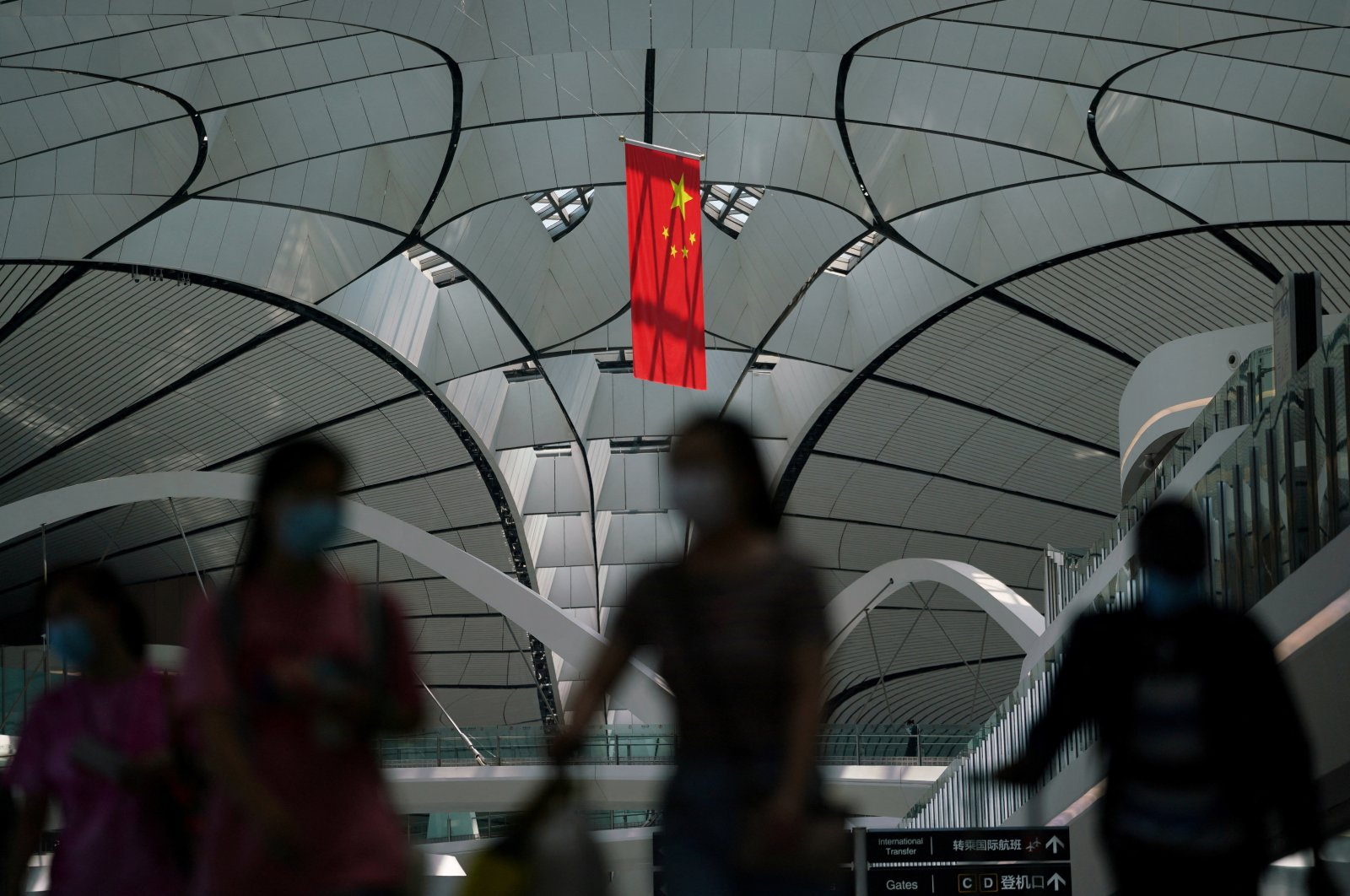People wearing face masks following the coronavirus disease (COVID-19) outbreak walk under a Chinese flag at Beijing Daxing International Airport in Beijing, China, July 24, 2020. (Reuters Photo)
