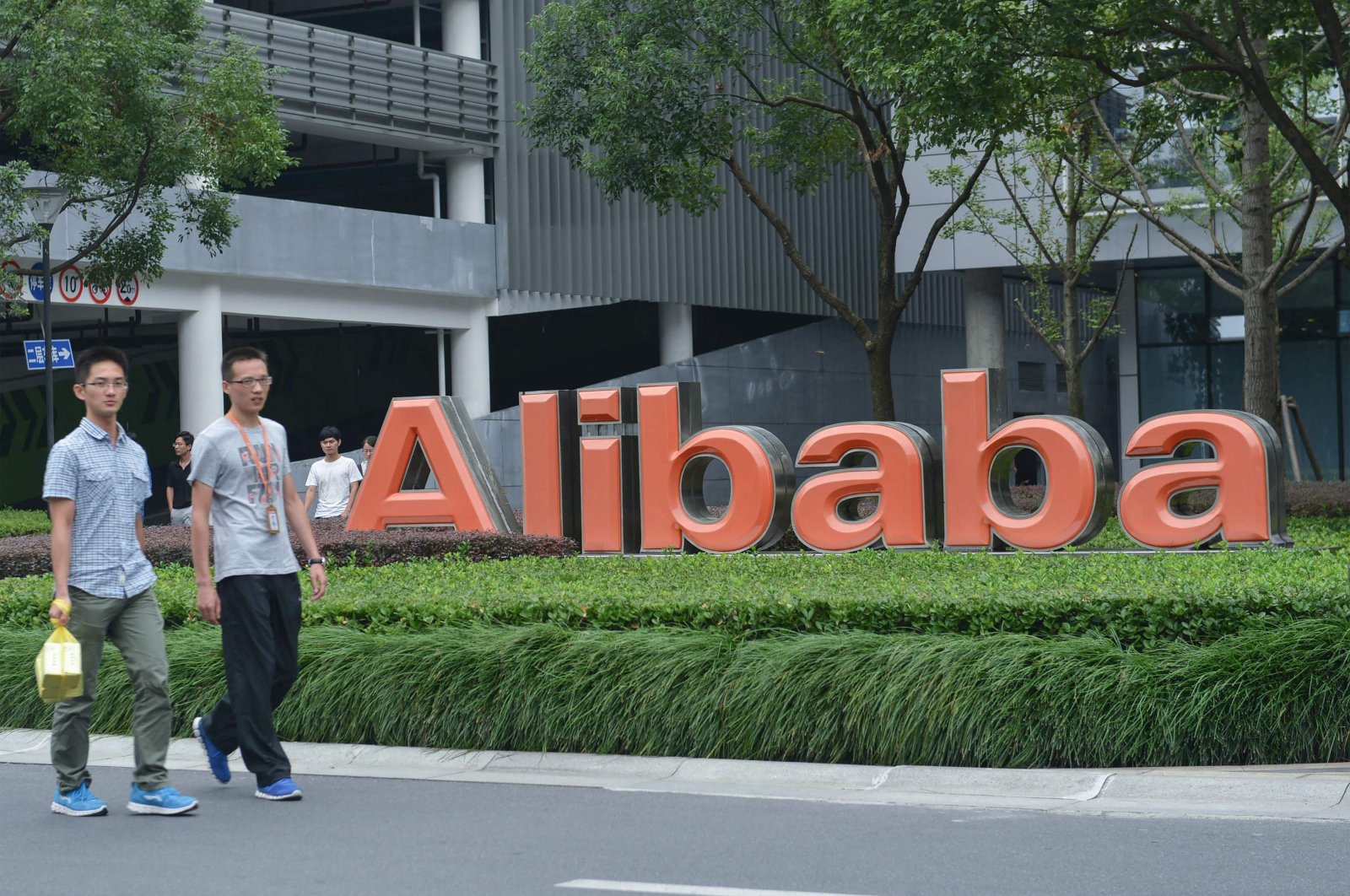 Staff members walk past the logo of Chinese e-commerce giant Alibaba at its headquarters in Hangzhou, in China&#039;s eastern Zhejiang province, May 27, 2022. (AFP Photo)
