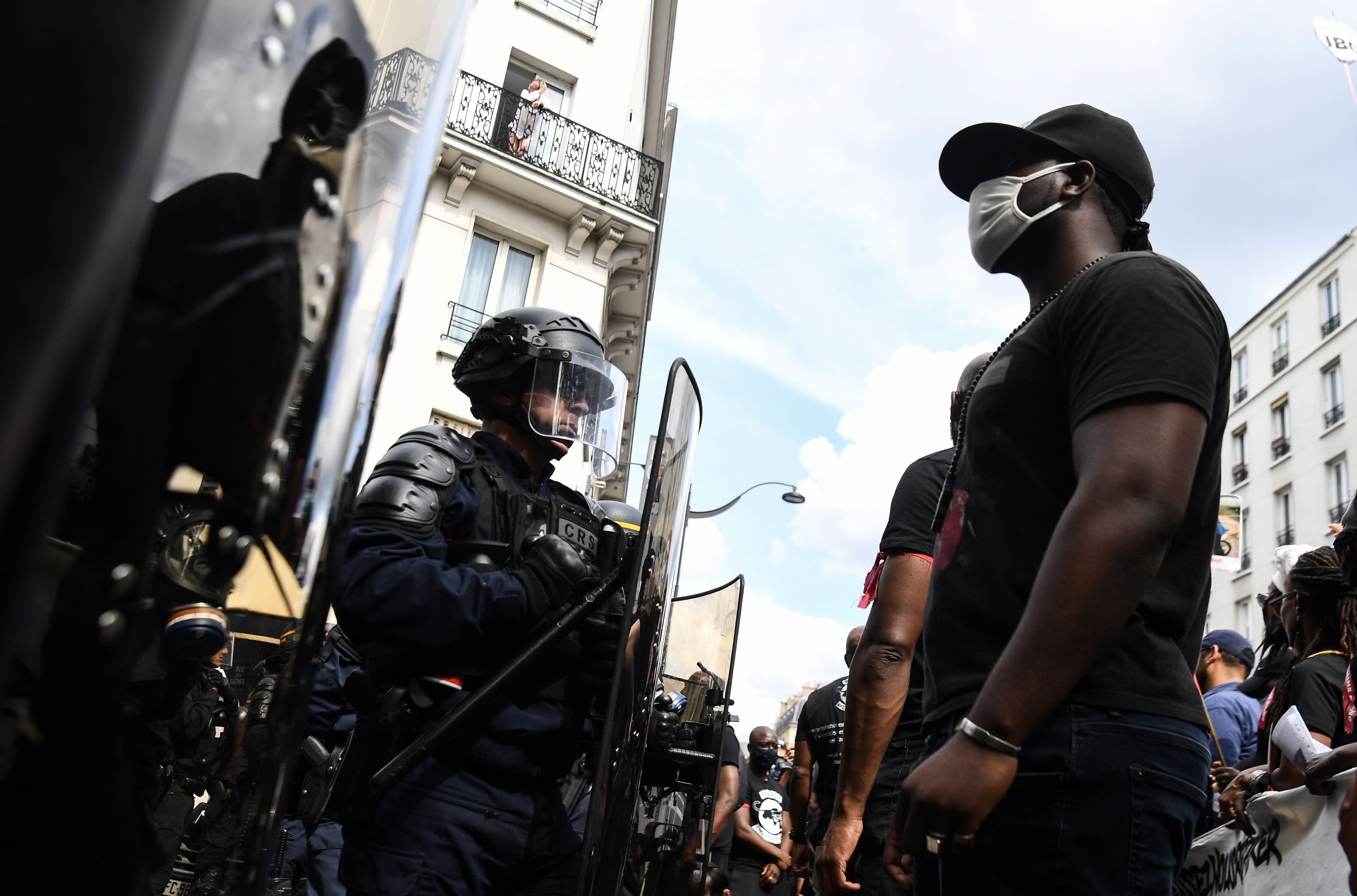 Seorang pengunjuk rasa yang mengenakan masker berdiri di depan polisi selama demonstrasi menentang rasisme dan kebrutalan polisi, di Paris, 20 Juni 2020. (Foto File AFP)
