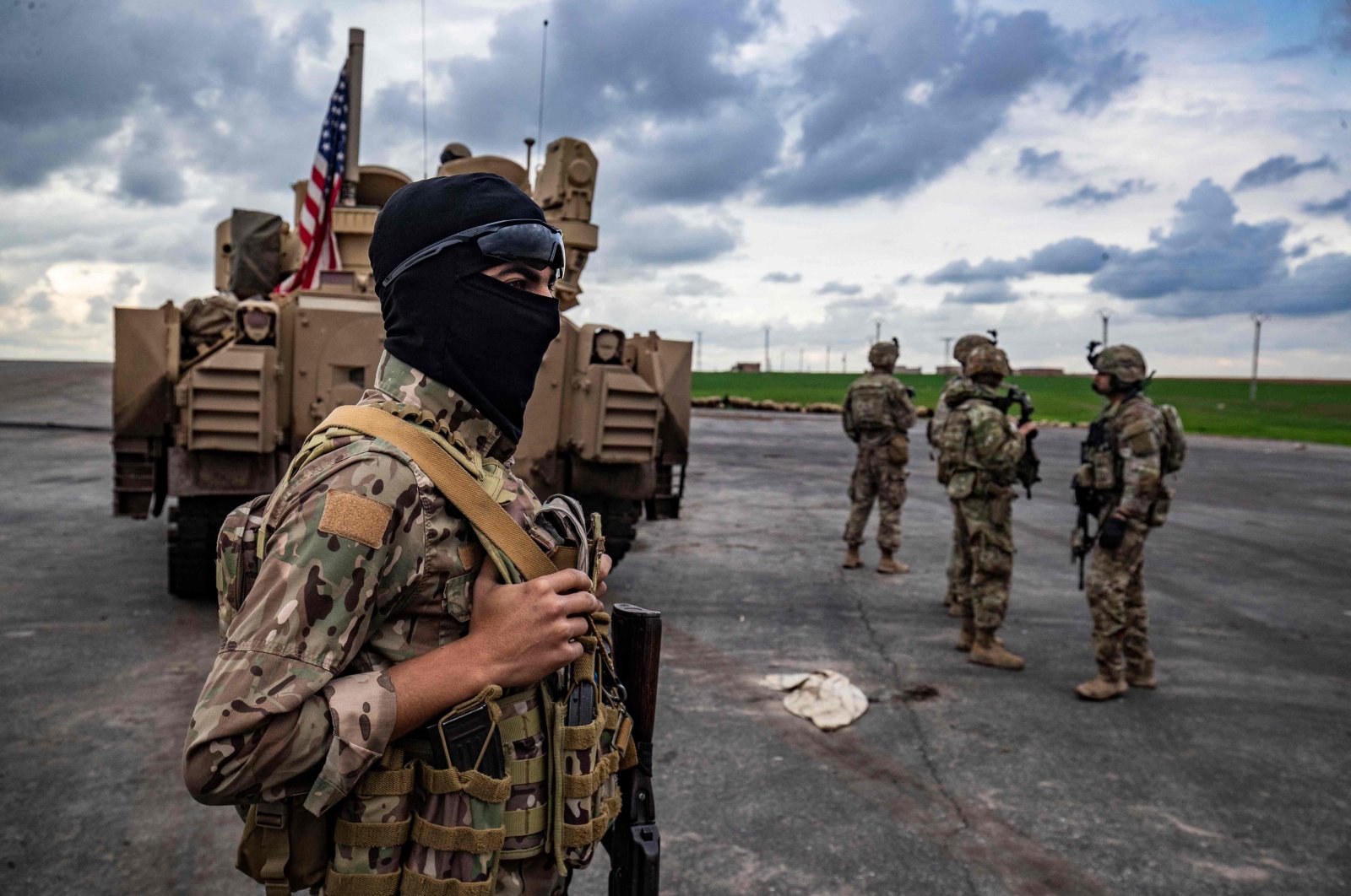 A PKK/YPG terrorist (L) and U.S. soldiers near an armored military vehicle in Hassakeh, Syria, March 27, 2023. (AFP Photo)