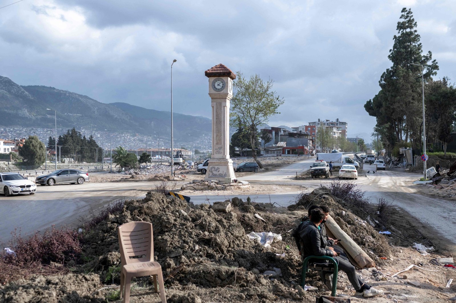 People sit next to a clock tower in Hatay still standing after stopping at 4:10 a.m. following a 7.7-magnitude earthquake on Feb. 6, 2023, in Hatay, southeastern Türkiye, March 28, 2023. (AFP Photo)