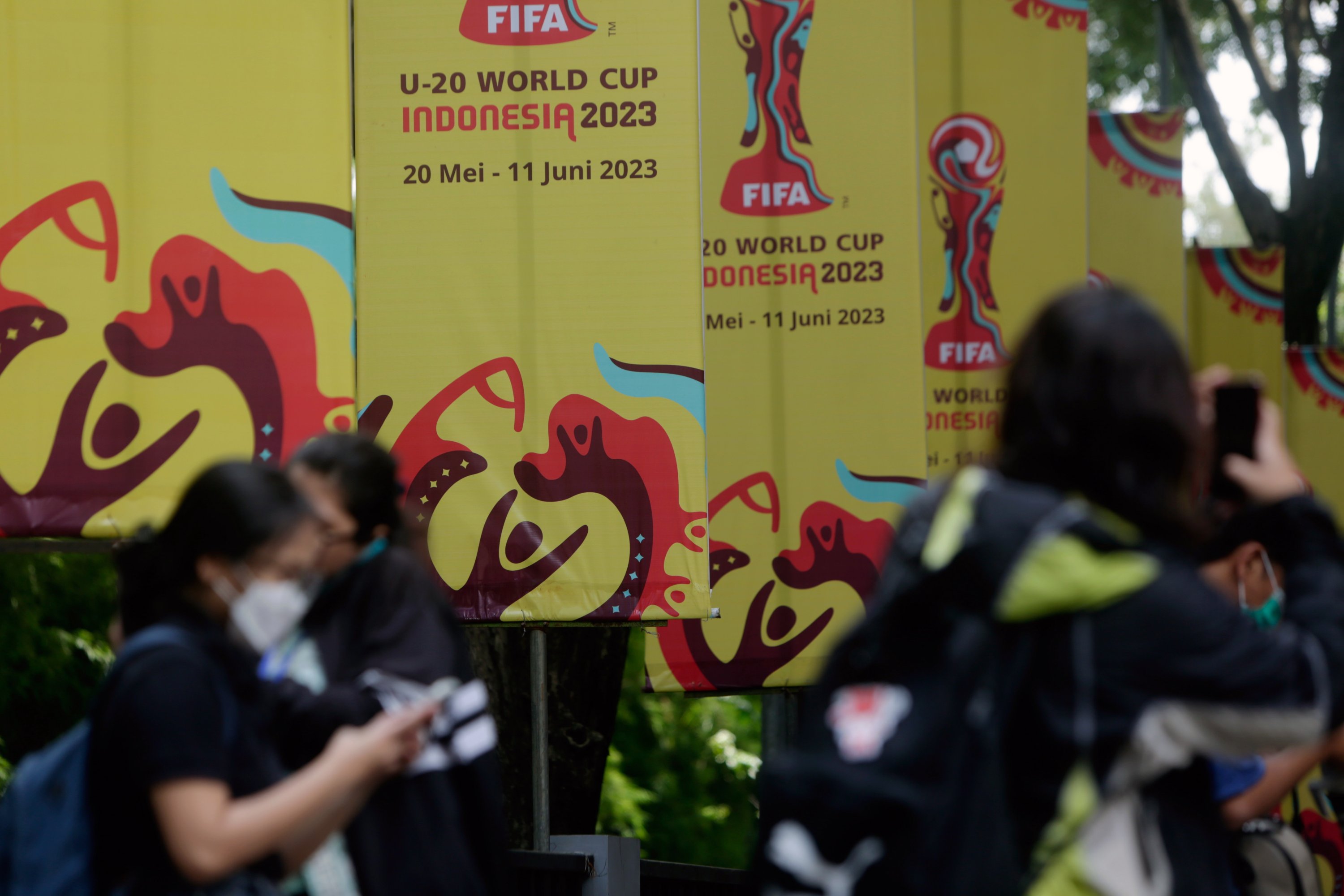Para pekerja berdiri di depan spanduk Piala Dunia U-20 setelah FIFA mencabut status tuan rumah Indonesia untuk Piala Dunia U-20 2023, di arena olahraga, Jakarta, Indonesia, 30 Maret 2023. (Foto EPA)