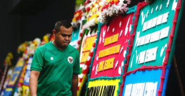 A dejected man walks past flower wreaths left by Indonesian football supporters as a sign of mourning following FIFA revoking Indonesia's hosting status for the 2023 U-20 World Cup, at a sport arena, Jakarta, Indonesia, March 30, 2023. (EPA Photo)