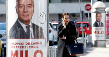 A women uses her phone as she passes by pre-election posters of long-time incumbent Milo Djukanovic, Podgorica, Montenegro, March 30, 2023. (Reuters Photo)