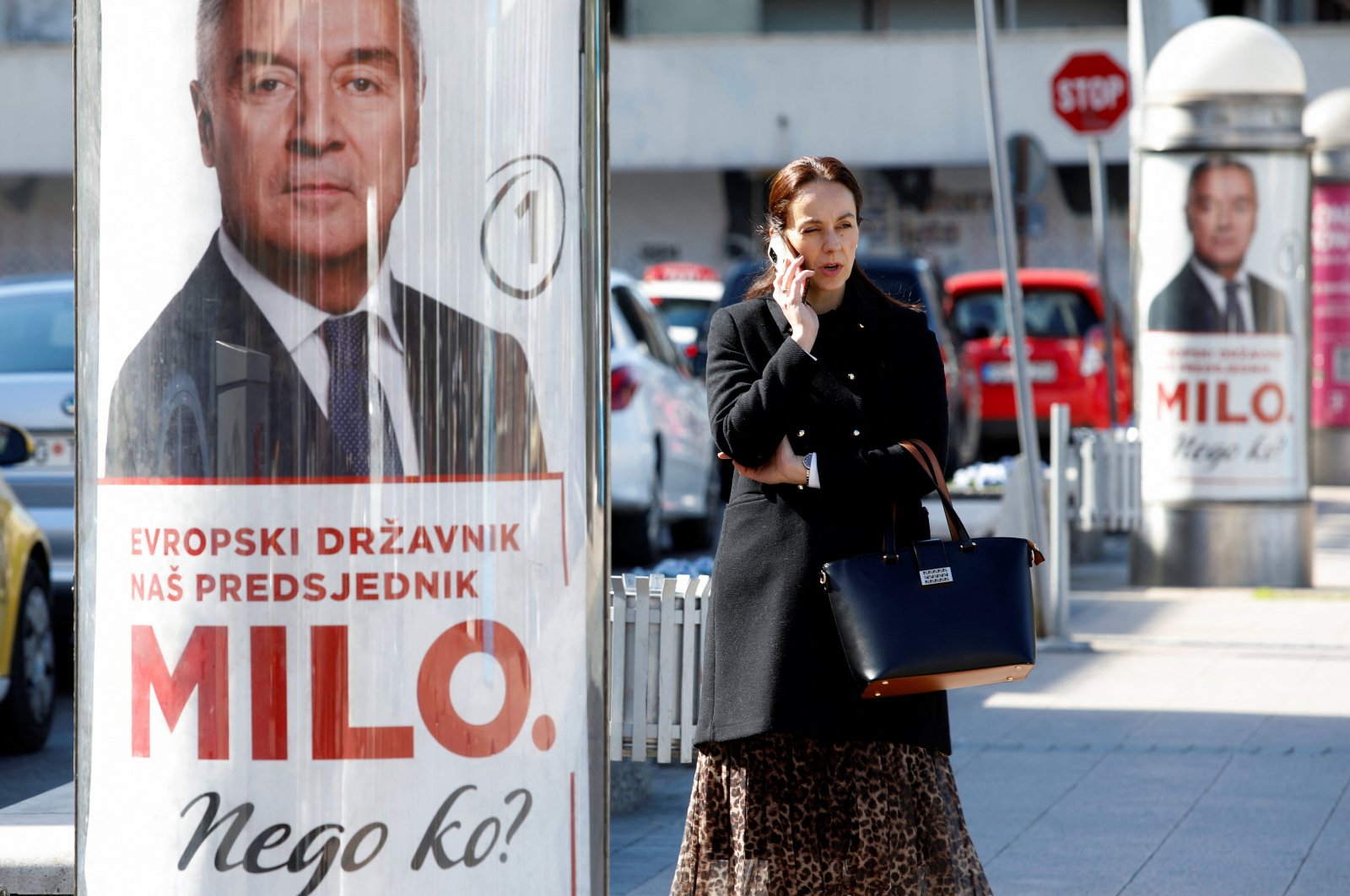 A women uses her phone as she passes by pre-election posters of long-time incumbent Milo Djukanovic, Podgorica, Montenegro, March 30, 2023. (Reuters Photo)