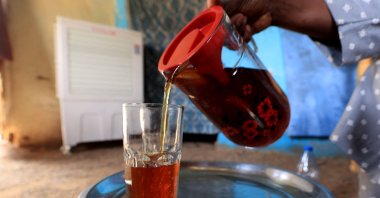 A Sudanese woman pours a glass of Helo Murr, a Ramadan drink made with dried corn and spices which is then dipped in water, Khartoum, March 20, 2023. (AFP Photo)