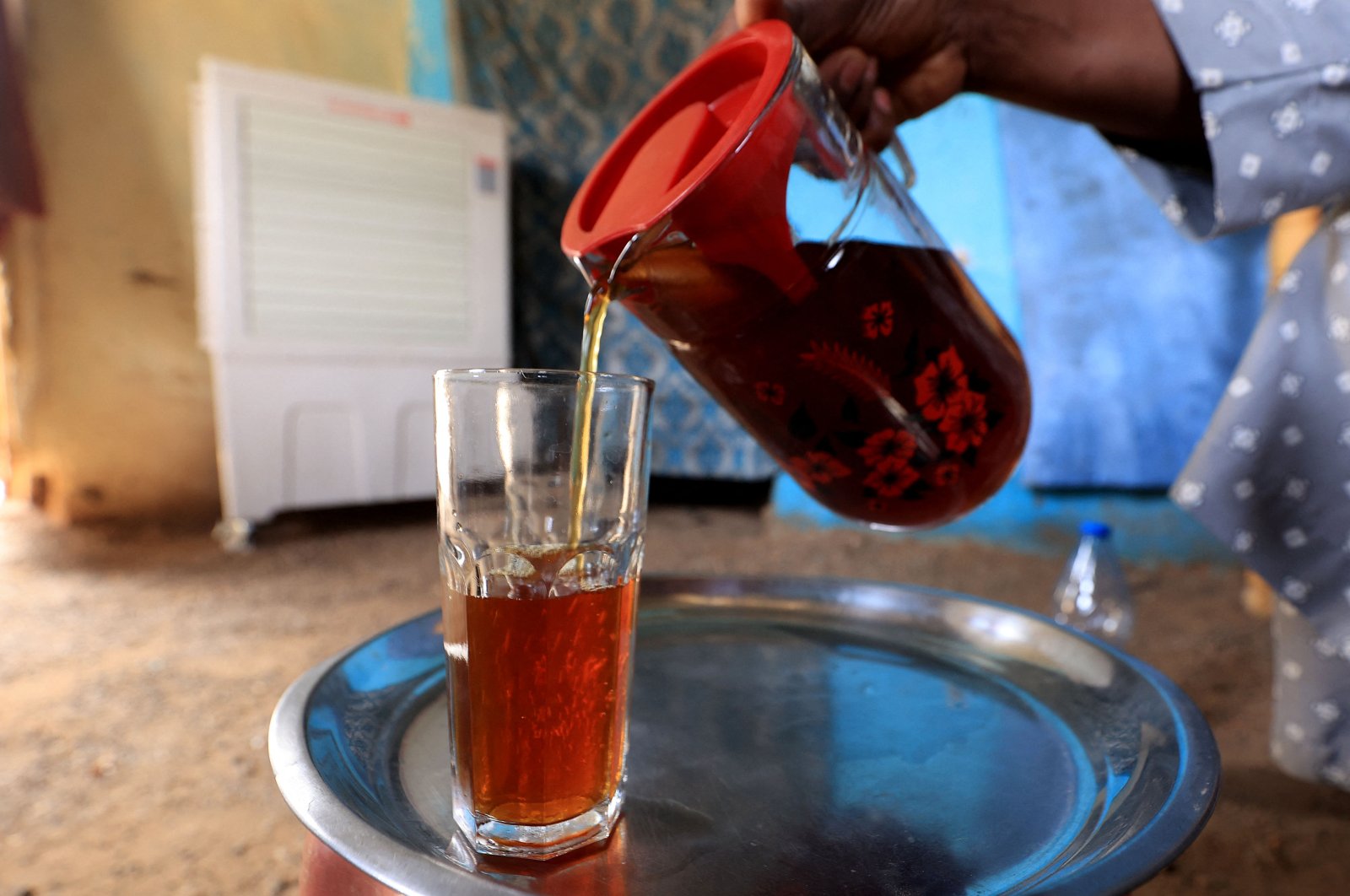 A Sudanese woman pours a glass of Helo Murr, a Ramadan drink made with dried corn and spices which is then dipped in water, Khartoum, March 20, 2023. (AFP Photo)