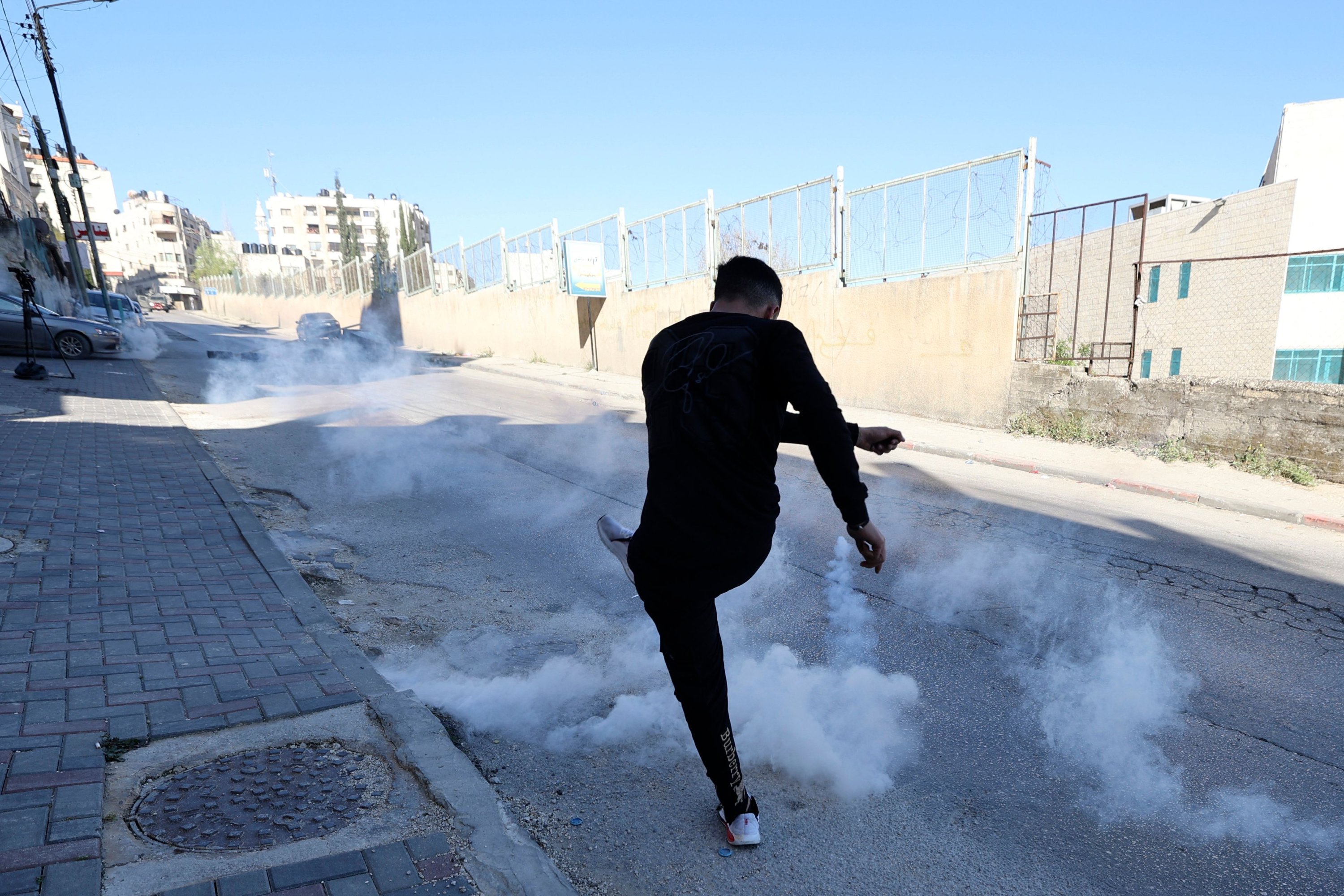 Seorang Palestina menendang tabung gas air mata ke arah tentara Israel selama bentrokan di Nablus, Tepi Barat yang diduduki, 3 April 2023. (Foto AFP)