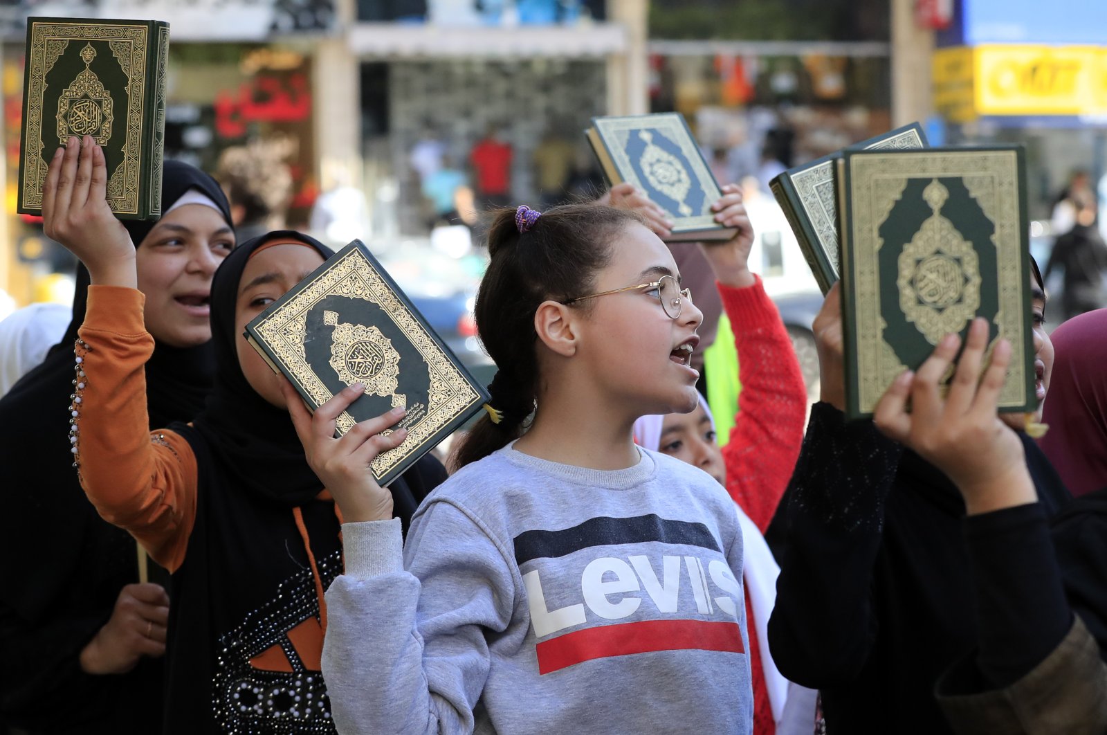 Muslim girls hold up the Islamic holy book "Quran," during street performances in Sidon, Lebanon, April 1, 2023. (AP Photo)