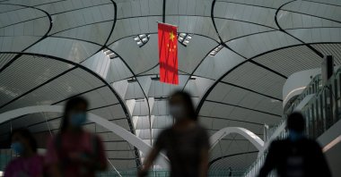 People wearing face masks following the COVID-19 outbreak walk under a Chinese flag at Beijing Daxing International Airport in Beijing, China, July 24, 2020. (Reuters Photo)
