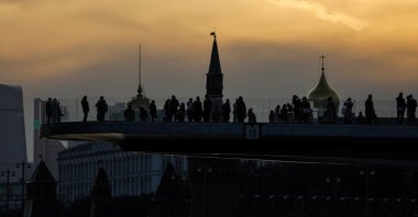 People watch sunset on a bridge with the Kremlin in the background in Moscow, Russia, April 5, 2023. (Reuters Photo)
