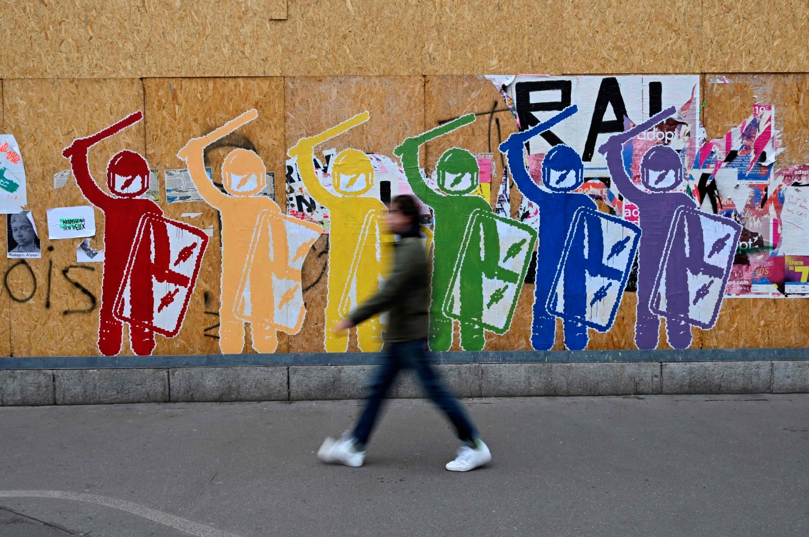 A pedestrian passes by posters of anti-riot policemen ahead of a demonstration on the 11th day of action after the government pushed a pensions reform through parliament without a vote, using Article 49.3 of the constitution, in Rennes, western France, April 6, 2023. (AFP Photo)