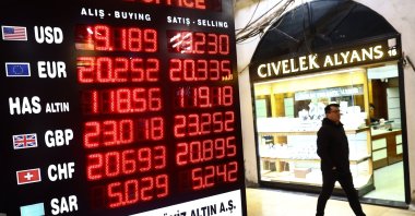 A man walks past a board displaying exchange rates at a currency exchange office in Istanbul, Türkiye, March 15, 2023. (EPA Photo)