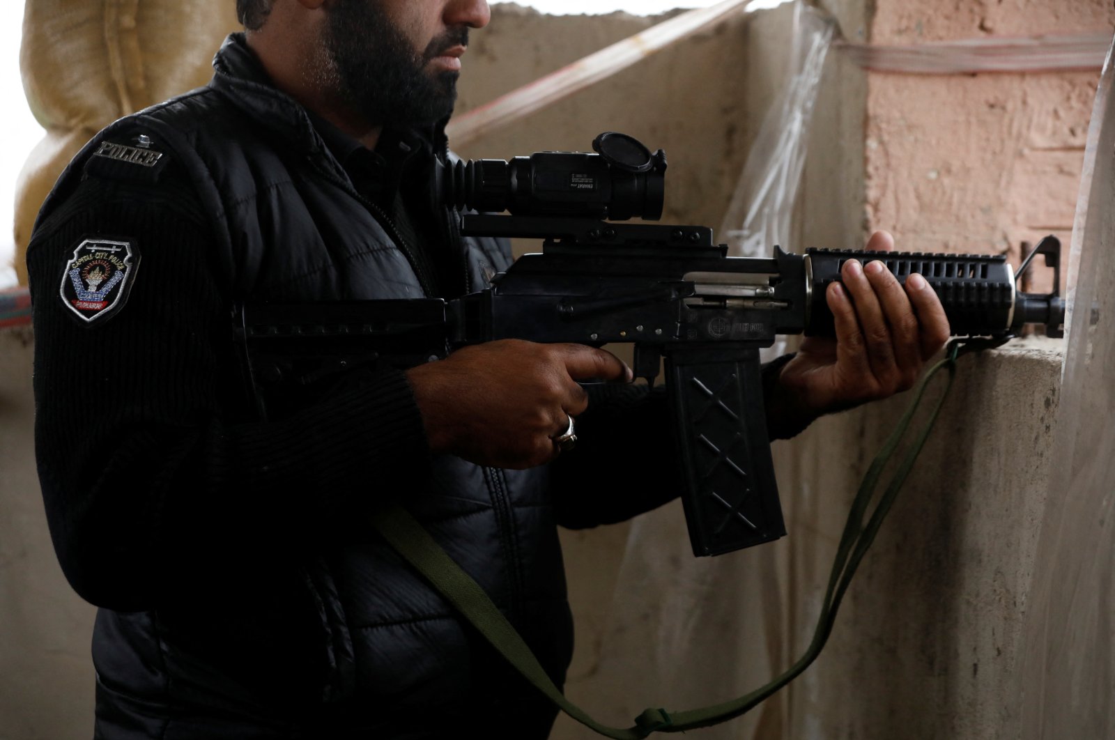 A police officer holds a machine gun with thermal binoculars attached to it, on the rooftop of Sangu outpost, in the outskirts of Peshawar, Pakistan, Feb. 9, 2023. (Reuters File Photo)