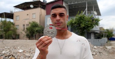 Barış Üstün shows his Türkiye Bodybuilding and Fitness Championship silver medal in front of his destroyed house, Hatay, Türkiye, April 10, 2023. (AA Photo)