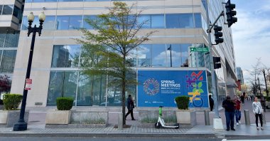 People walk past a sign for the 2023 Spring Meetings of the World Bank/International Monetary Fund on the IMF building in Washington, D.C., U.S., April 5, 2023. (AFP Photo)