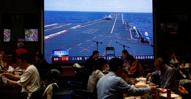 Customers dine near a giant screen broadcasting news footage of an aircraft taking off from China's Shandong aircraft carrier, Beijing, China, April 10, 2023. (Reuters Photo)