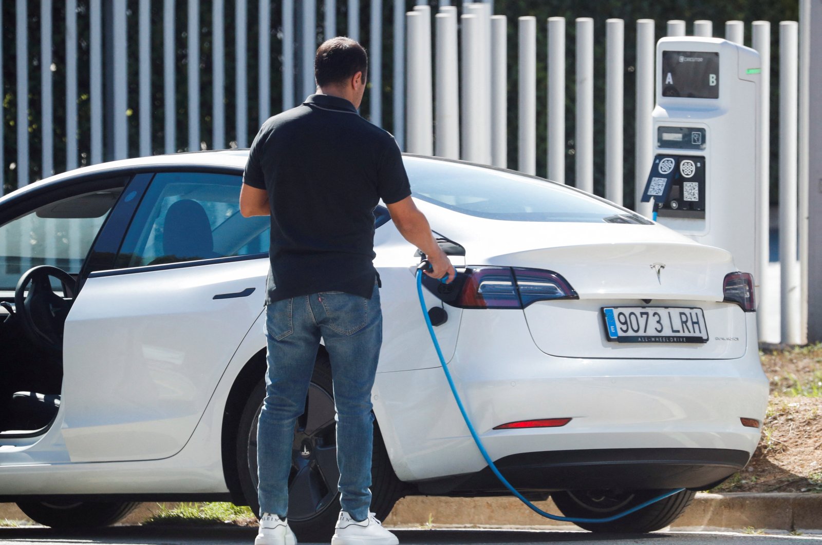 A man removes a cable after charging a Tesla electric car at a public charging point in Sant Cugat del Valles, near Barcelona, Spain, Sept. 17, 2021. (Reuters Photo)