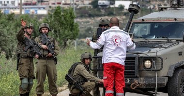 A Palestinian ambulance first responder speaks with Israeli soldiers blocking a road at a location where 2 Palestinians were killed during an Israeli army operation, Nablus, occupied West Bank, April 11, 2023. (AFP Photo)