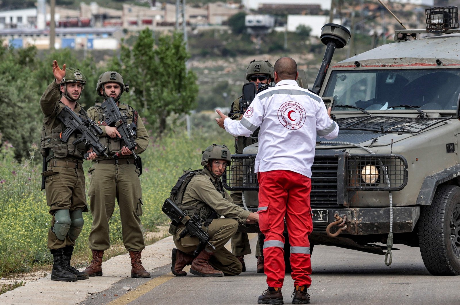 A Palestinian ambulance first responder speaks with Israeli soldiers blocking a road at a location where 2 Palestinians were killed during an Israeli army operation, Nablus, occupied West Bank, April 11, 2023. (AFP Photo)