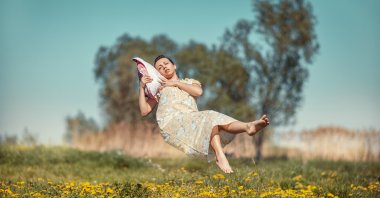 Girl lying on a cushion hovers over the field in weightlessness. (Shutterstock Photo)