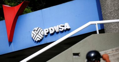 A man walks past a gas station with the logo of the Venezuelan state oil company PDVSA in Caracas, Venezuela, Dec. 23, 2016. (Reuters Photo)