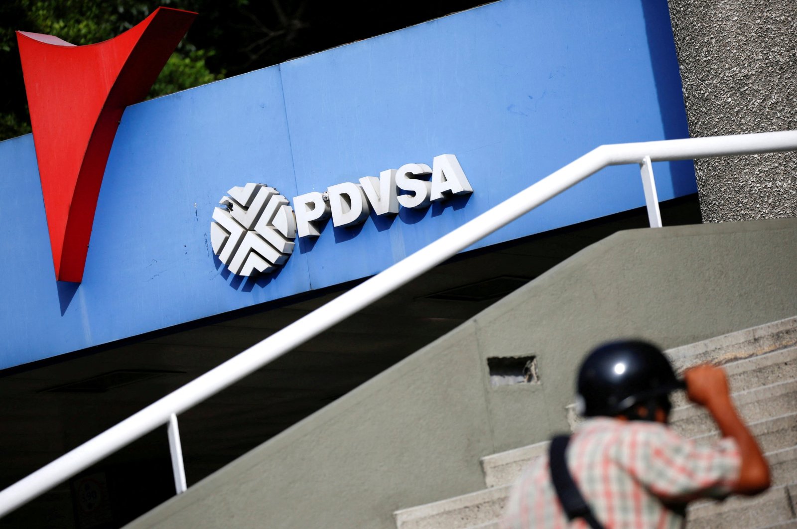 A man walks past a gas station with the logo of the Venezuelan state oil company PDVSA in Caracas, Venezuela, Dec. 23, 2016. (Reuters Photo)