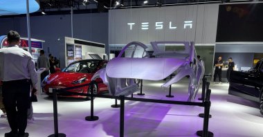 A man stands next to a Tesla Model 3 electric vehicle (EV) display at the third China International Consumer Products Expo, in Haikou, Hainan province, China, April 12, 2023. (Reuters Photo)
