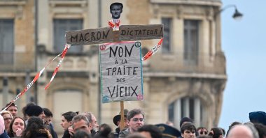Protesters hold a placard that reads, "Macron, dictator. No to the slavery of the elderly" during a demonstration in Rennes, northwestern France, April 13, 2023. (AFP Photo)
