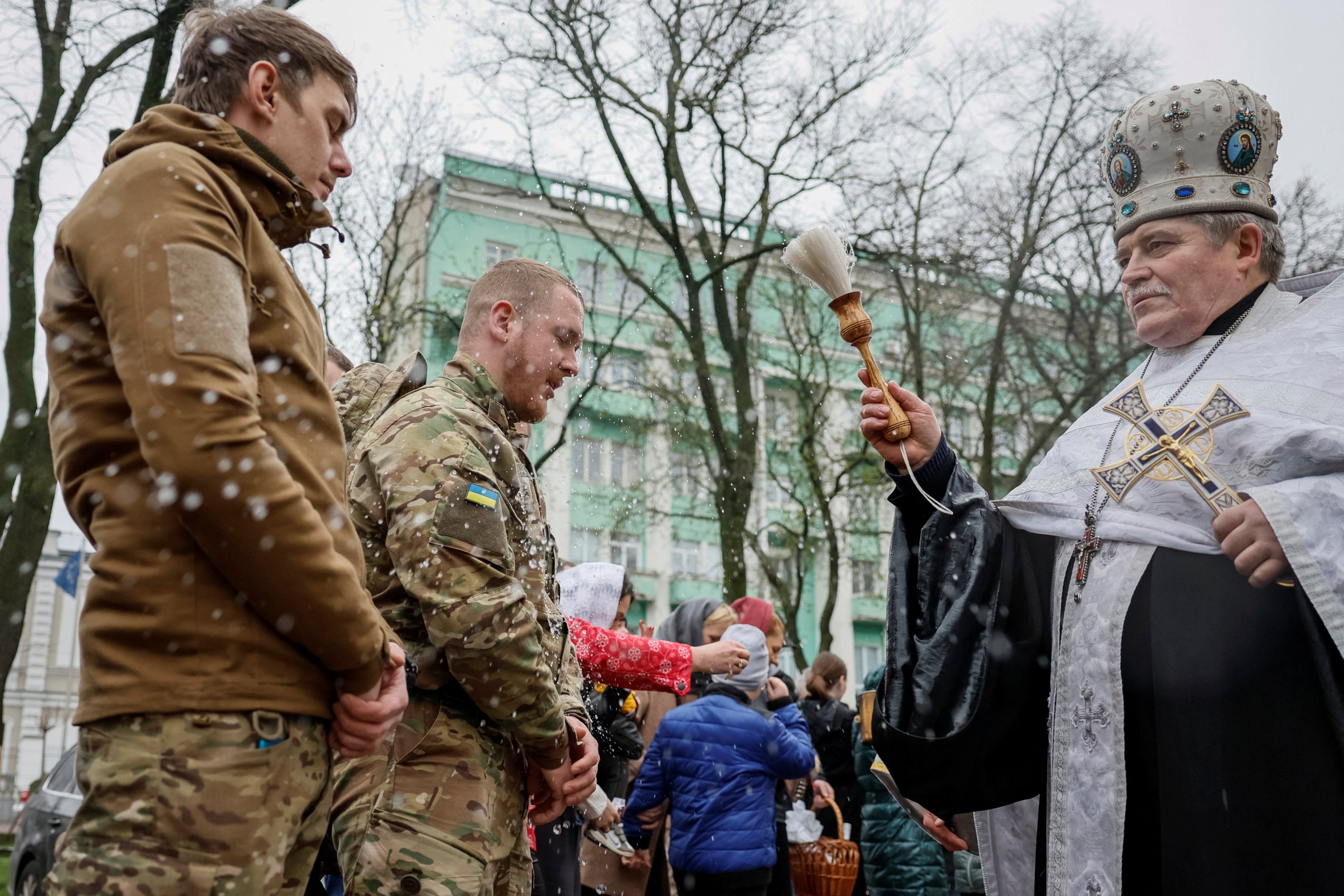 Seorang pendeta Ortodoks menyemprotkan air suci ke tentara selama kebaktian yang menandai Paskah Ortodoks, di tengah invasi Rusia ke Ukraina, di Kyiv, Ukraina, 16 April 2023. (Foto Reuters)
