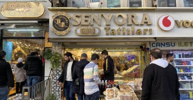 People shop in front of a confectionary store, Senyora Tatlıları, in Istanbul, Türkiye, April 14, 2023. 