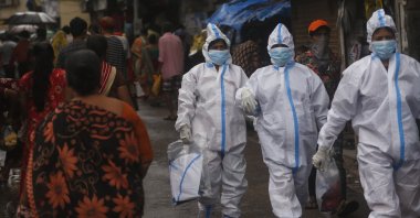 Health workers return after screening people for COVID-19 symptoms in Dharavi, Mumbai, India, Aug. 11, 2020. (AP Photo)