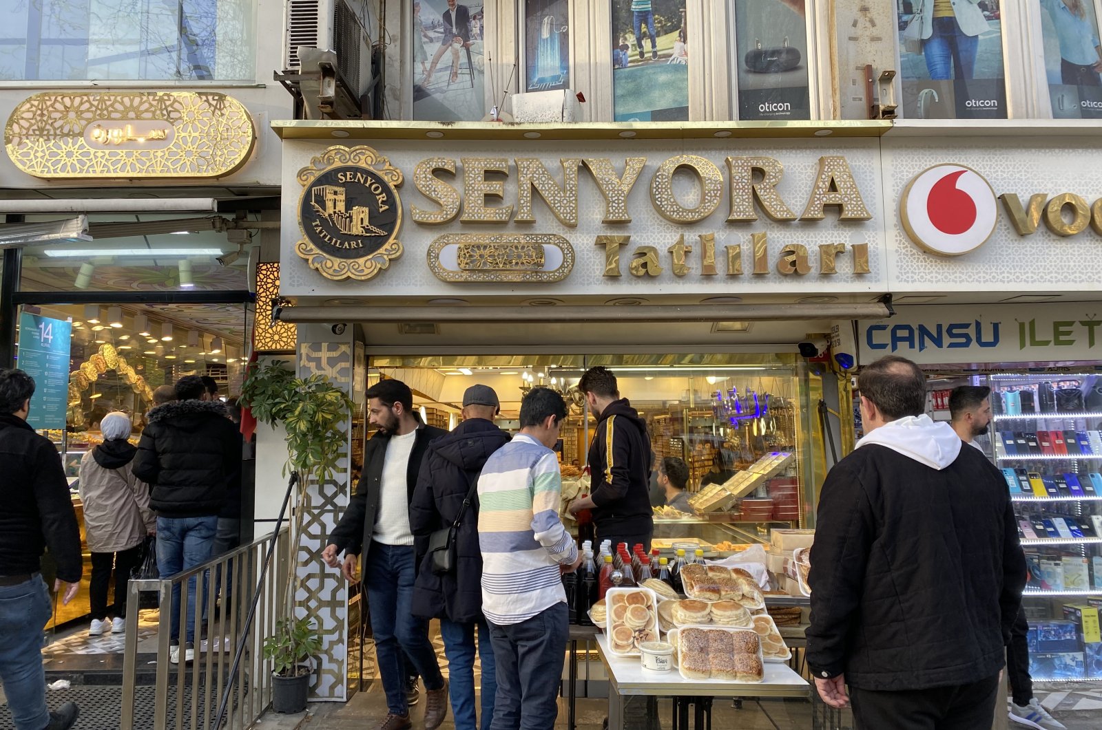 People shop in front of a confectionary store, Senyora Tatlıları, in Istanbul, Türkiye, April 14, 2023. 