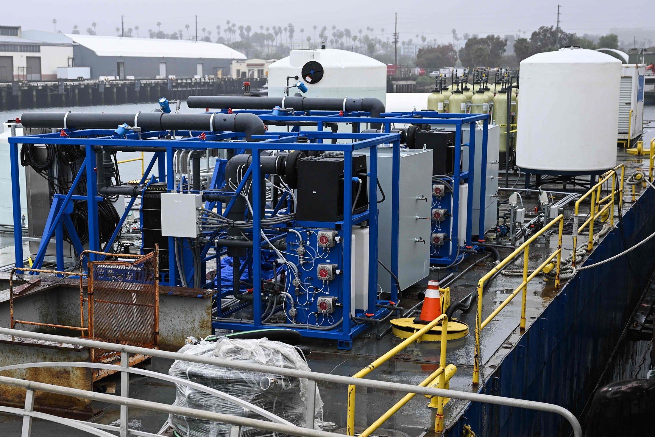 Peralatan, termasuk reaktor elektrokimia tempat air laut dipecah melalui elektrolisis untuk menangkap karbon, dimuat ke tongkang, di San Pedro, California, AS, 12 April 2023. (Foto AFP)