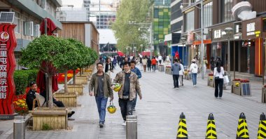 People walk along a shopping district in Beijing, China, April 17, 2023. (EPA Photo)