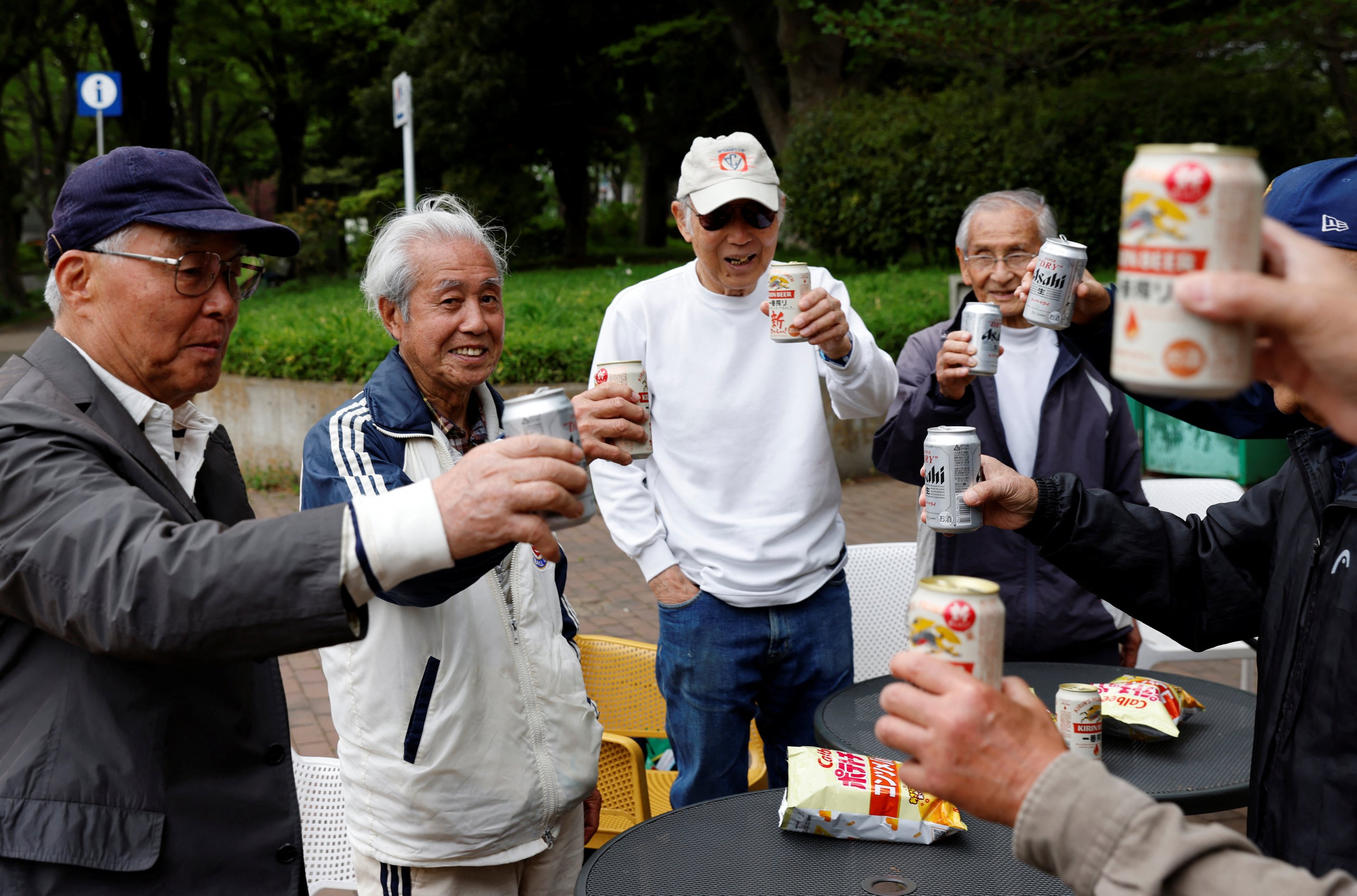 Gelandang Red Star Mutsuhiko Nomura (kiri ke-2) dan rekan satu timnya bersulang dengan bir kalengan di sebuah taman setelah pertandingan pembukaan SFL (Soccer For Life) 80 League, Tokyo, Jepang, 12 April 2023. (Foto Reuters)