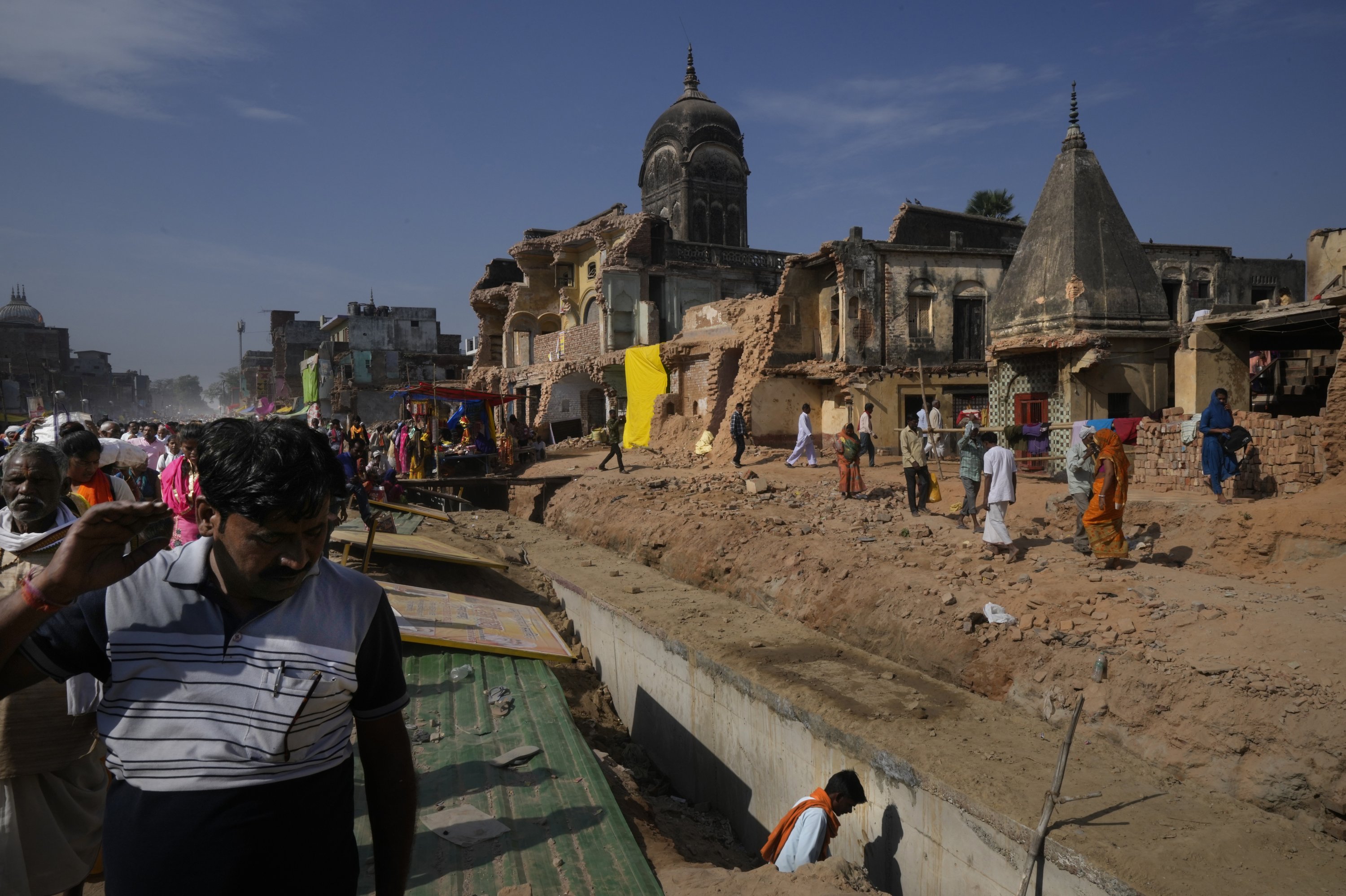 Umat ​​berjalan di samping deretan bangunan yang dihancurkan untuk membuat jalan lebih lebar dalam pembangunan kembali kota, Ayodhya, India, 30 Maret 2023. (Foto AP)