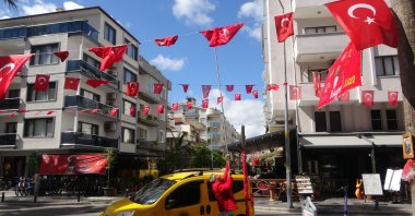 A man helps decorate a street with Turkish flags as part of traditional preparations for the Children's Day celebrations, in Muğla, western Türkiye, April 19, 2023. (IHA Photo)