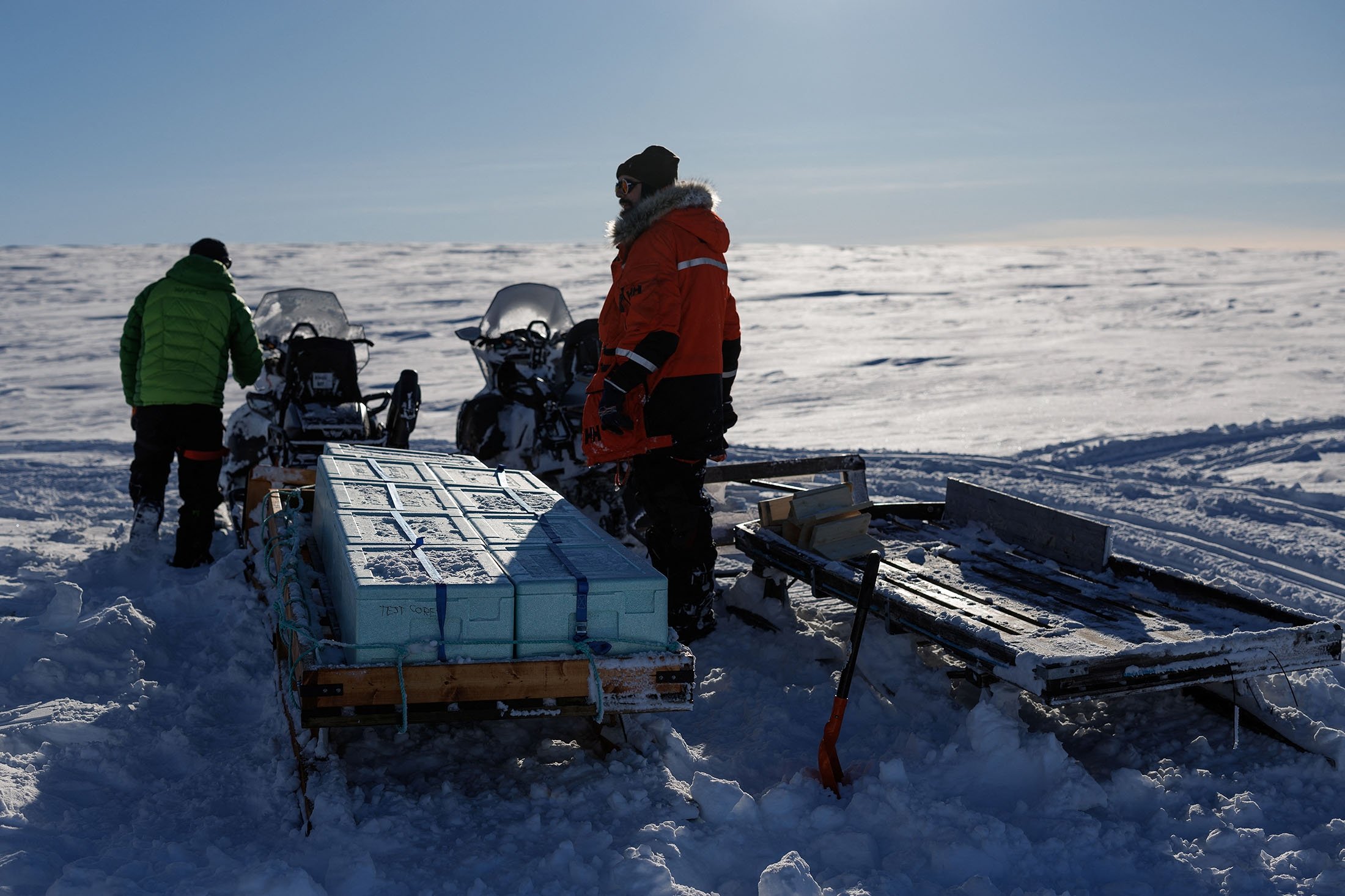Ahli glasiologi Jean-Charles Gallet (kanan), 41, dan Federico Scoto mengendarai sepeda motor saat mereka menarik kereta luncur berisi kotak berisi inti es yang menunggu untuk dibawa kembali untuk disimpan ke Ny-Aalesund, Svalbard, Norwegia, 10 April 2023. (Reuters Photo )