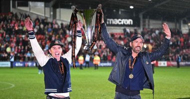 U.S. actors and Wrexham co-owners Rob McElhenney (L) and Ryan Reynolds (R) celebrate on the pitch with the National League trophy after the English National League football match between Wrexham and Boreham Wood at the Racecourse Ground Stadium in Wrexham, northern Wales, April 22, 2023. (AFP Photo)
