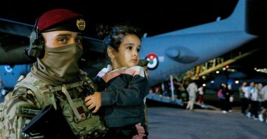 A Jordanian soldier carries a child as people are evacuated from Sudan disembark an aircraft at a military airport in Amman, Jordan, April 24, 2023. (AFP Photo)