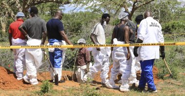 Kenyan homicide detectives and forensic experts examine exhumed bodies from several shallow mass graves in Kilifi, Kenya, April 23, 2023. (EPA Photo)