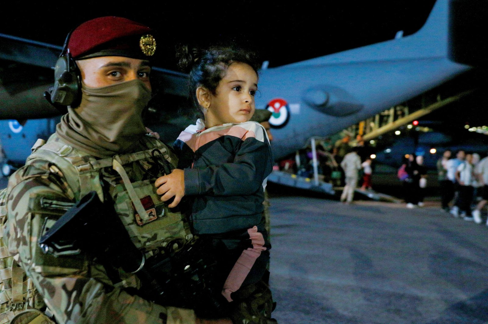 A Jordanian soldier carries a child as people are evacuated from Sudan disembark an aircraft at a military airport in Amman, Jordan, April 24, 2023. (AFP Photo)