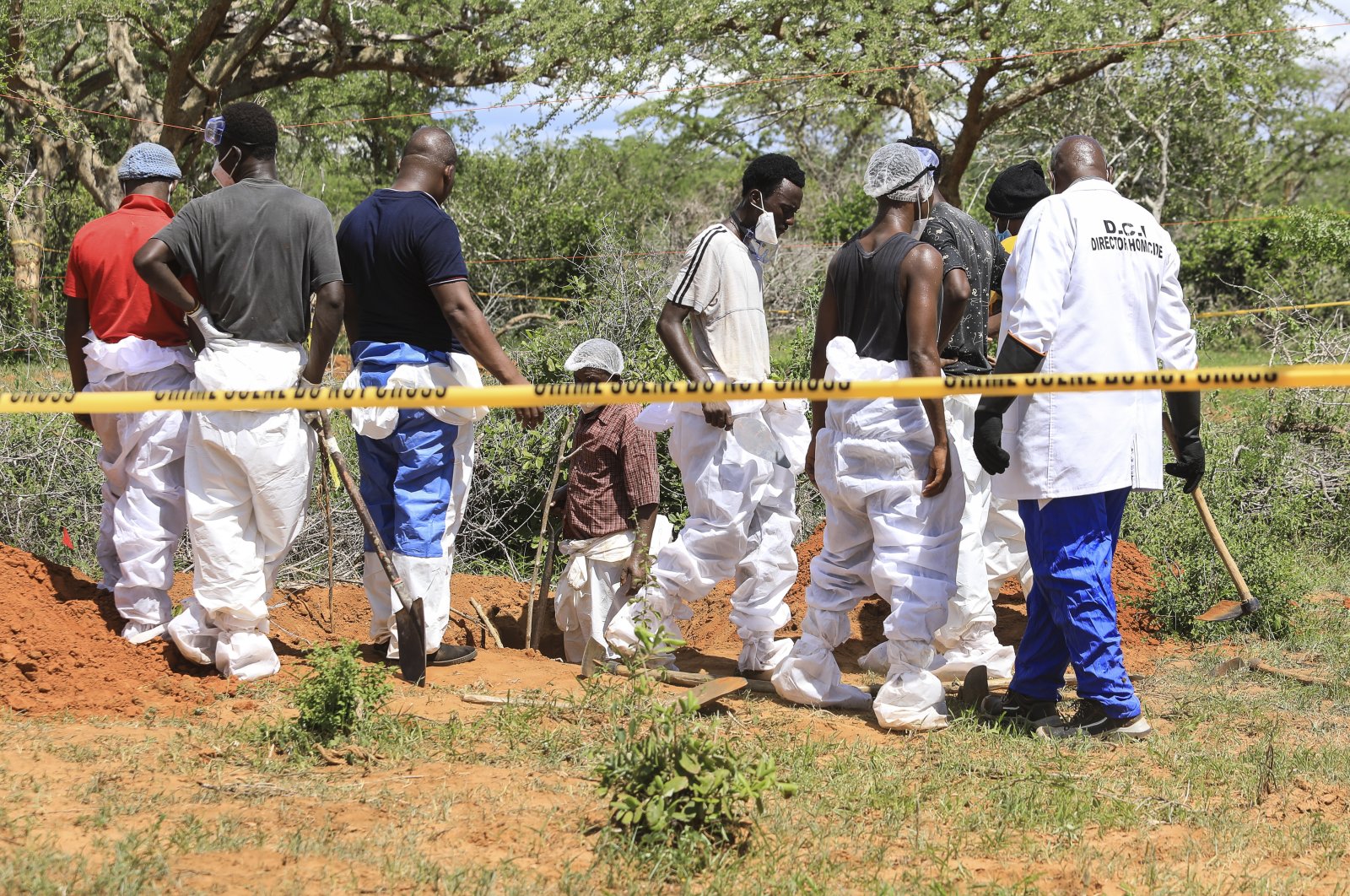 Kenyan homicide detectives and forensic experts examine exhumed bodies from several shallow mass graves in Kilifi, Kenya, April 23, 2023. (EPA Photo)