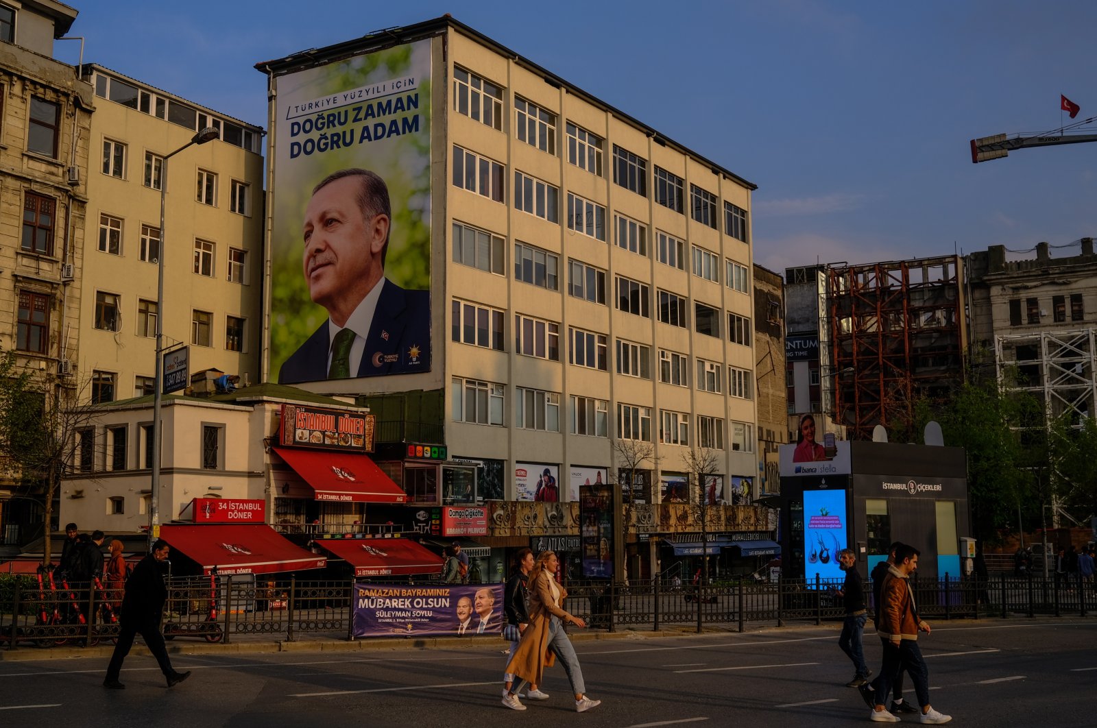People walk past an election poster of President Recep Tayyip Erdoğan in Istanbul, Türkiye, April 19, 2023. (EPA Photo)
